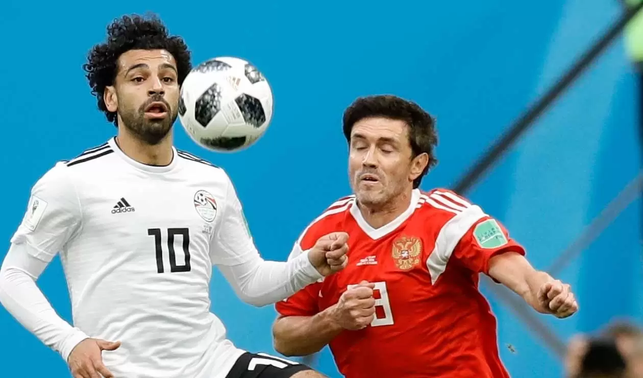 El egipcio Mohamed Salah defiende un balón con Yuri Shirkov de Rusia