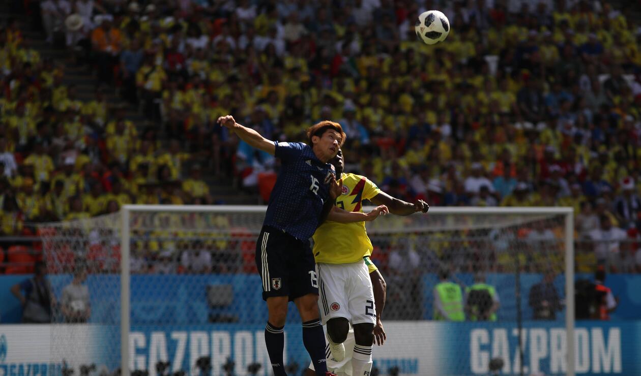 Pelota dividida entre un jugador colombiano y otro japonés durante la primera mitad