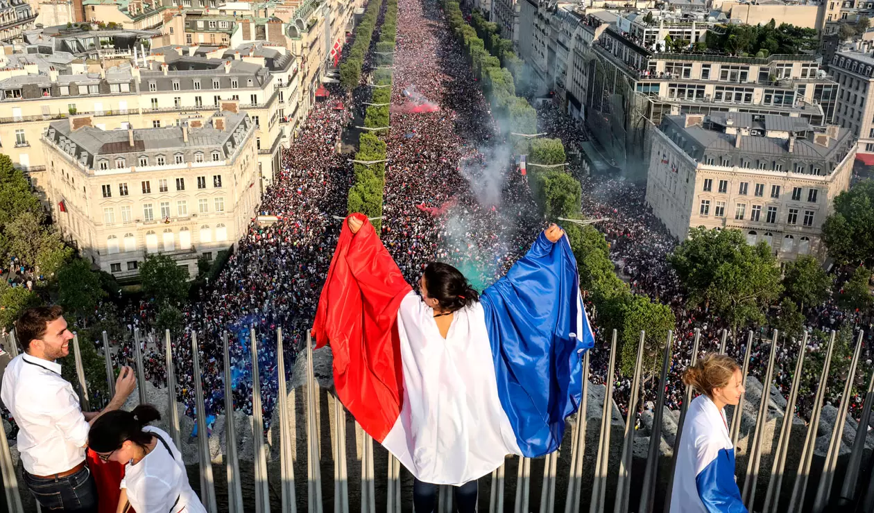 Una hincha de Francia exhibe la bandera por las calles de París