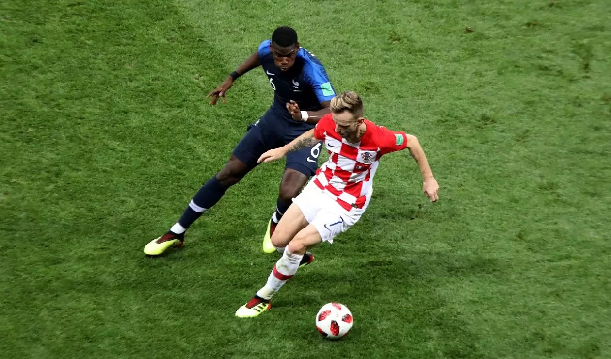 Ivan Rakitić defiende una pelota pretendida por Paul Pogba  