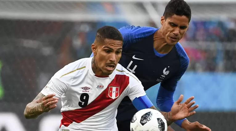 El peruano Paolo Guerrero defiende el balón ante el acoso del francés Raphael Varane 